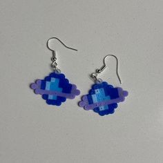 a pair of blue and purple earrings on a white surface