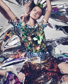 a woman with her hands up in the air, surrounded by shiny foil and mirrors