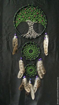 a green and white dream catcher with feathers on it's side next to a black background