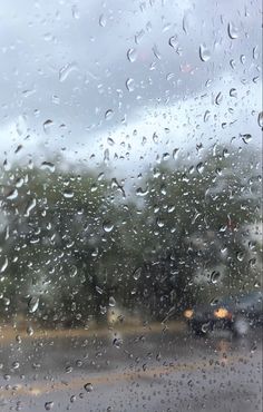 rain drops on the windshield of a car as it drives down a road in the rain