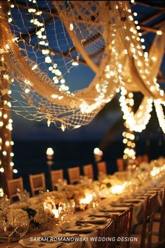 a long table is set up with candles and lights for an outdoor wedding reception in the evening