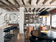 an industrial style living room and dining area with exposed ceilings, large windows, wooden beams, and modern furniture