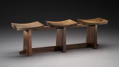 three wooden benches sitting next to each other on top of a gray floor covered in light