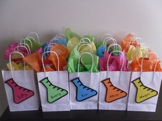 colorful paper bags with shoes on them are sitting on a shelf in front of a wall