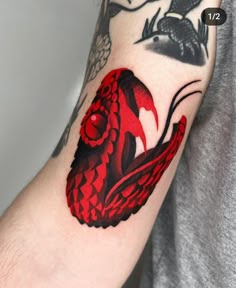 a man's arm with a red and black dragon tattoo on the left arm