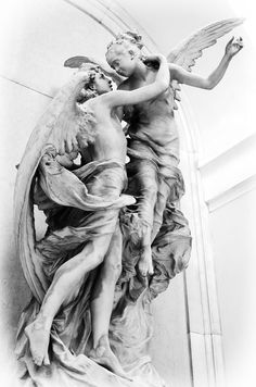 a statue of two cherubs with wings on the side of a building in black and white