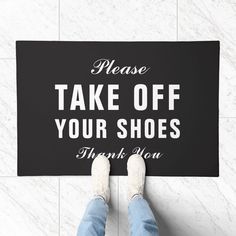 a person standing on the floor with a sign that says please take off your shoes thank you