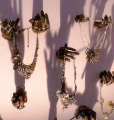 several different types of jewelry are arranged on a white surface with shadows from the wall