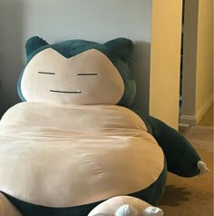 a large stuffed animal sitting on top of a floor next to pillows in the shape of animals