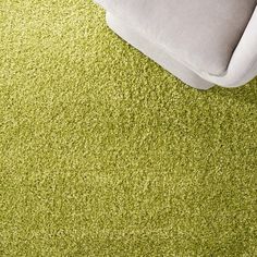 a green carpet with a white couch in the background