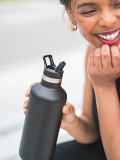 a woman is holding a water bottle and smiling