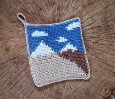 a crocheted pouch sitting on top of a wooden table next to a piece of wood