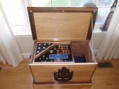 an open wooden box on the floor in front of a window