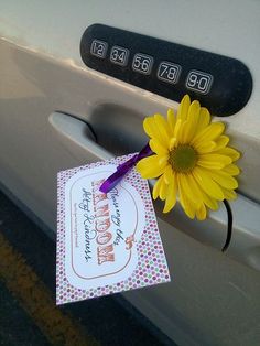 a yellow sunflower sticking out of the side of a car door