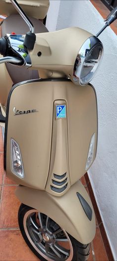 a tan scooter parked on the side of a building