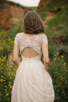 the back of a woman's dress as she walks through some wildflowers