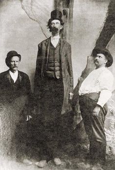 an old black and white photo of three men standing next to each other in front of a wall