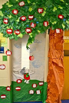 an apple themed classroom door decoration with apples on the front and back panels, hanging from a tree