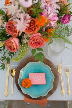 the table is set with colorful flowers and place settings