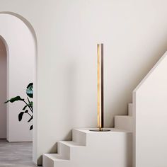 a white room with stairs and a plant in the corner on the right hand side