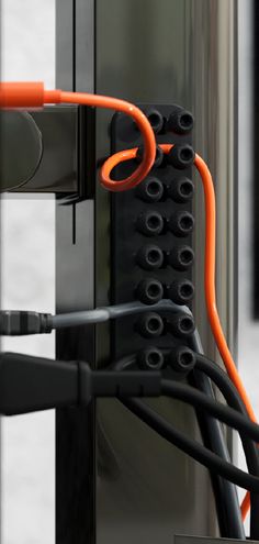 an orange and black electrical wire is connected to the side of a metal structure with wires