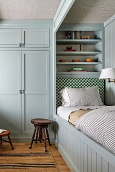 a bedroom with built in bookshelves next to a bed and stool on the floor