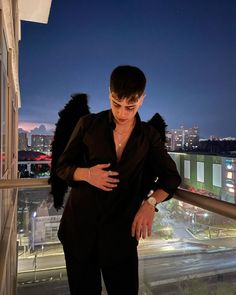 a woman standing on top of a balcony next to a window with city lights in the background