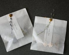 two pieces of white paper with flowers on them sitting next to each other in front of a black surface