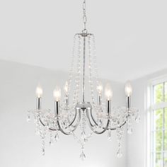 a crystal chandelier hanging from a ceiling in a room with white walls and windows