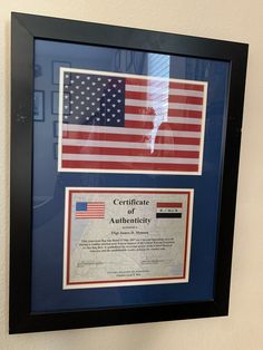 an american flag and certificate hanging on the wall in a black frame with blue border