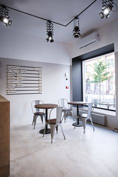 an empty room with tables and chairs in front of a large window that has a sign on the wall