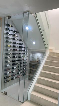 there is a wine rack on the wall next to stairs in this room with glass railings