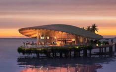 an artistic rendering of a floating restaurant on the water at sunset or dawn with palm trees in the foreground