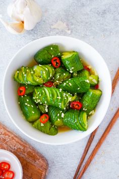 a white bowl filled with green vegetables next to chopsticks