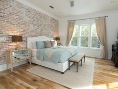 a bedroom with brick wall and white furniture