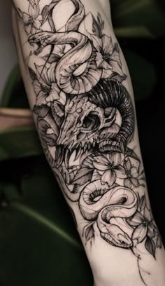 a tattoo design on the arm of a person with a snake and flowers around it