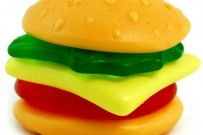 a toy hamburger made out of plastic on a white background with drops of water droplets