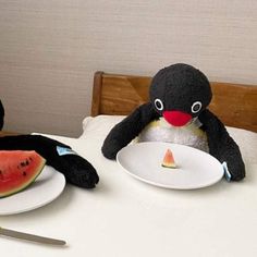 two stuffed animals sitting at a table with watermelon slices in front of them