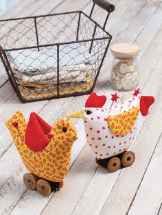 two small wooden chickens on wheels next to a basket with white and red polka dot fabric