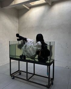 a woman laying on top of a glass table in an empty room with white walls