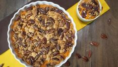 a pie sitting on top of a table next to two bowls filled with pecans