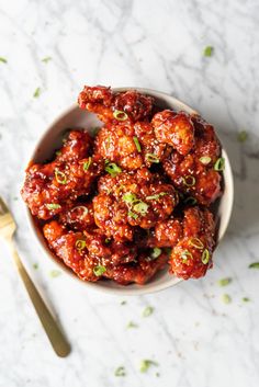 a white bowl filled with meat covered in sauce