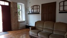 a living room filled with furniture next to a door and window on the side of a brick wall