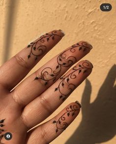 a person's hand with tattoos on their fingers and the shadow of a wall behind them