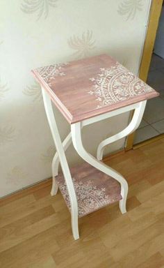 a pink and white table sitting on top of a hard wood floor next to a wall