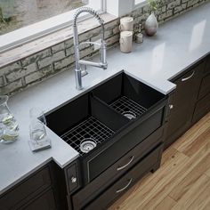 a kitchen sink sitting under a window next to a counter top with two glasses on it