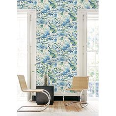 a room with blue and white wallpaper, two chairs and a plant in the corner