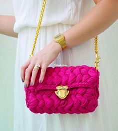 a woman's hand holding a pink purse with gold hardware and chain around it