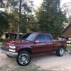 a maroon pick up truck parked in front of a house