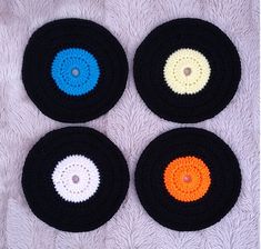 four crocheted coasters with different colored circles in them on a white surface